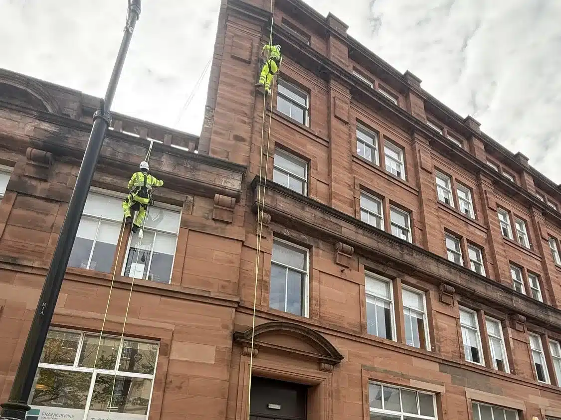 Two rope access technicians repointing at cornice level in Glasgow