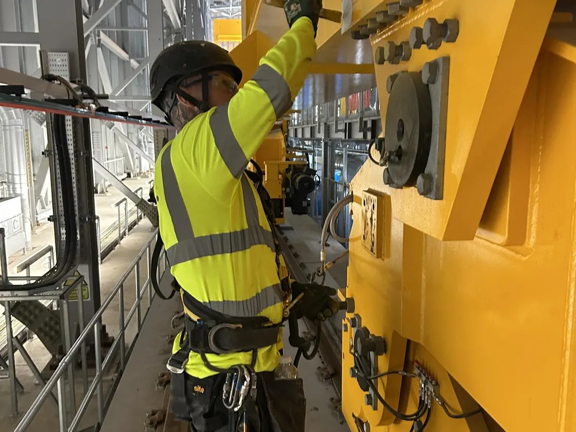 Technician greasing the end carriage of an overhead travelling crane
