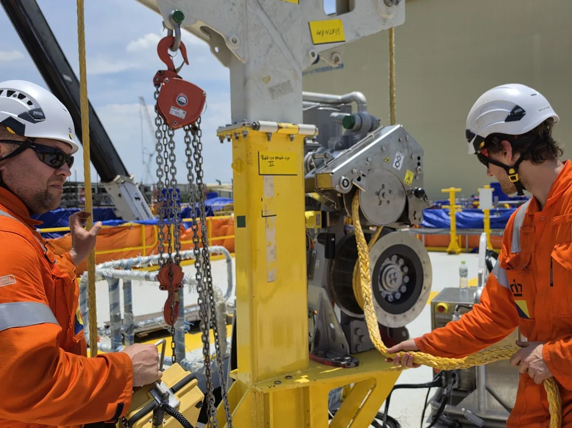 Technicians running a mock-up cable pull with a pulling frame at a fabrication yard