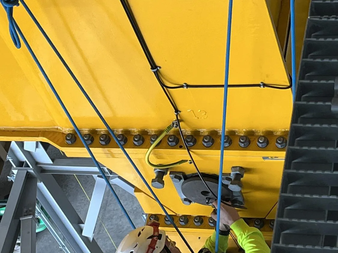 Rope access technician ascending beside an overhead crane girder