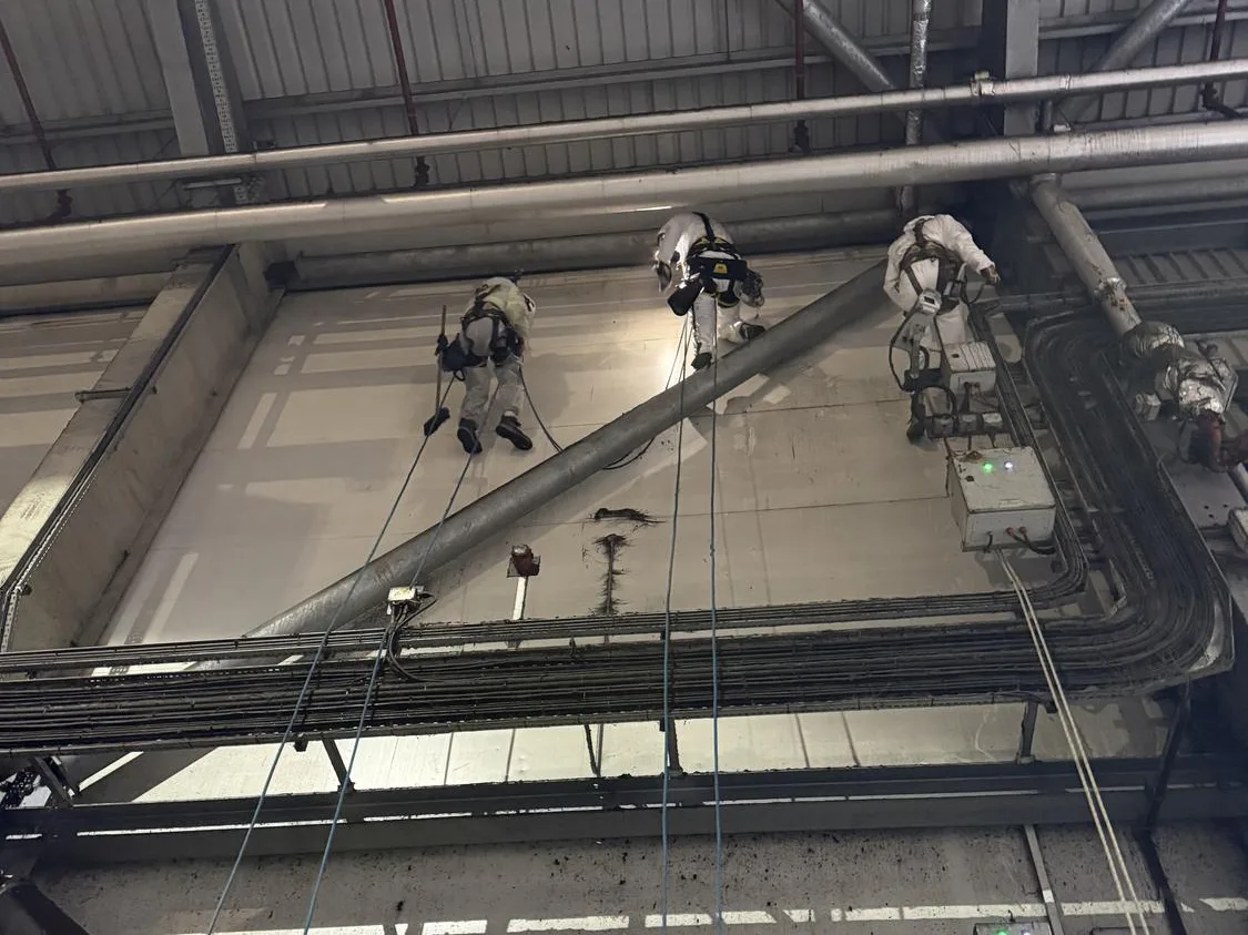 Rope access team cleaning roof structure at the materials recycling facility