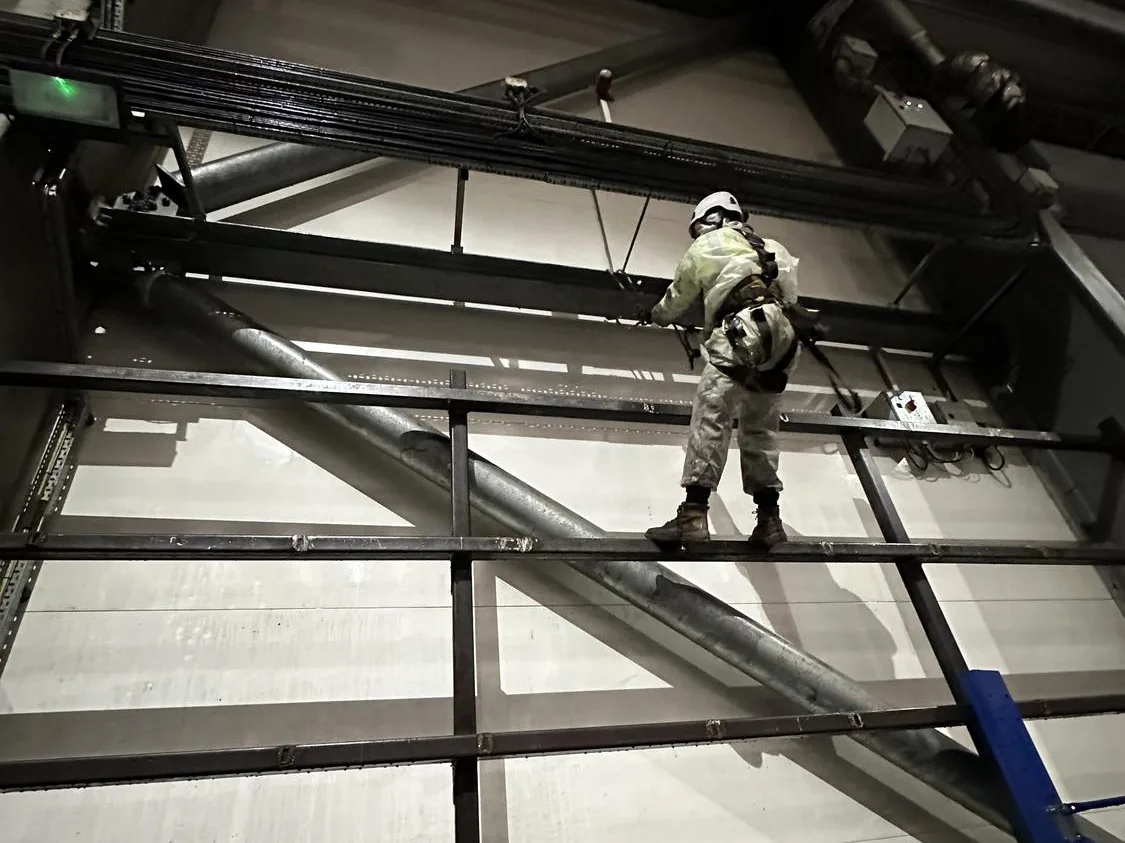 Technician cleaning roof steelwork above the processing hall