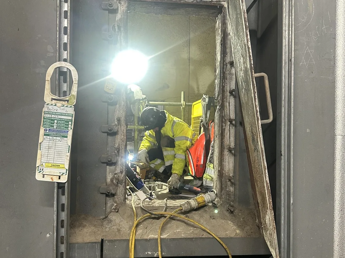 Technician working at a vessel hatch entry with task lighting